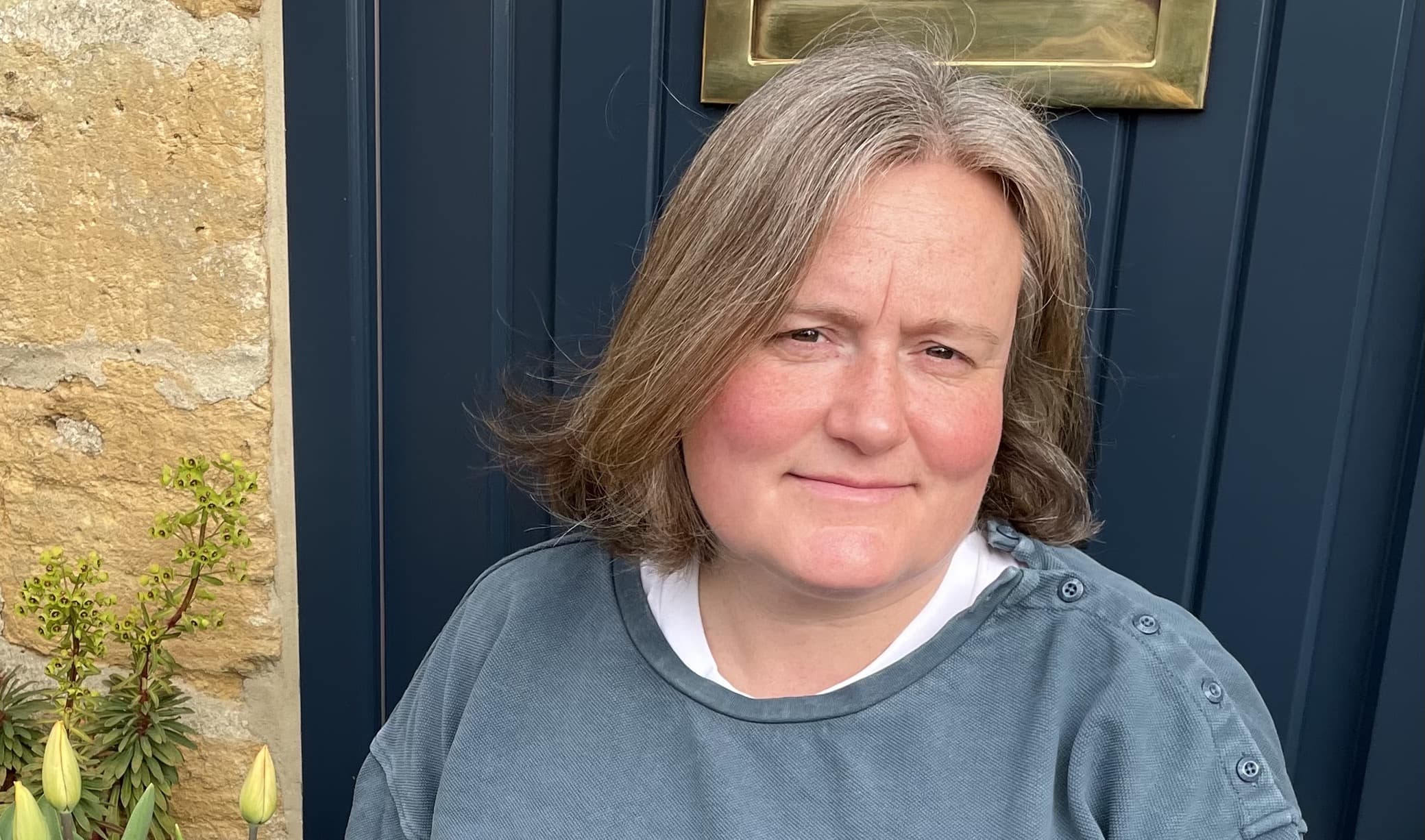 headshot of Kate Burtonwood taken in front of a dark blue door