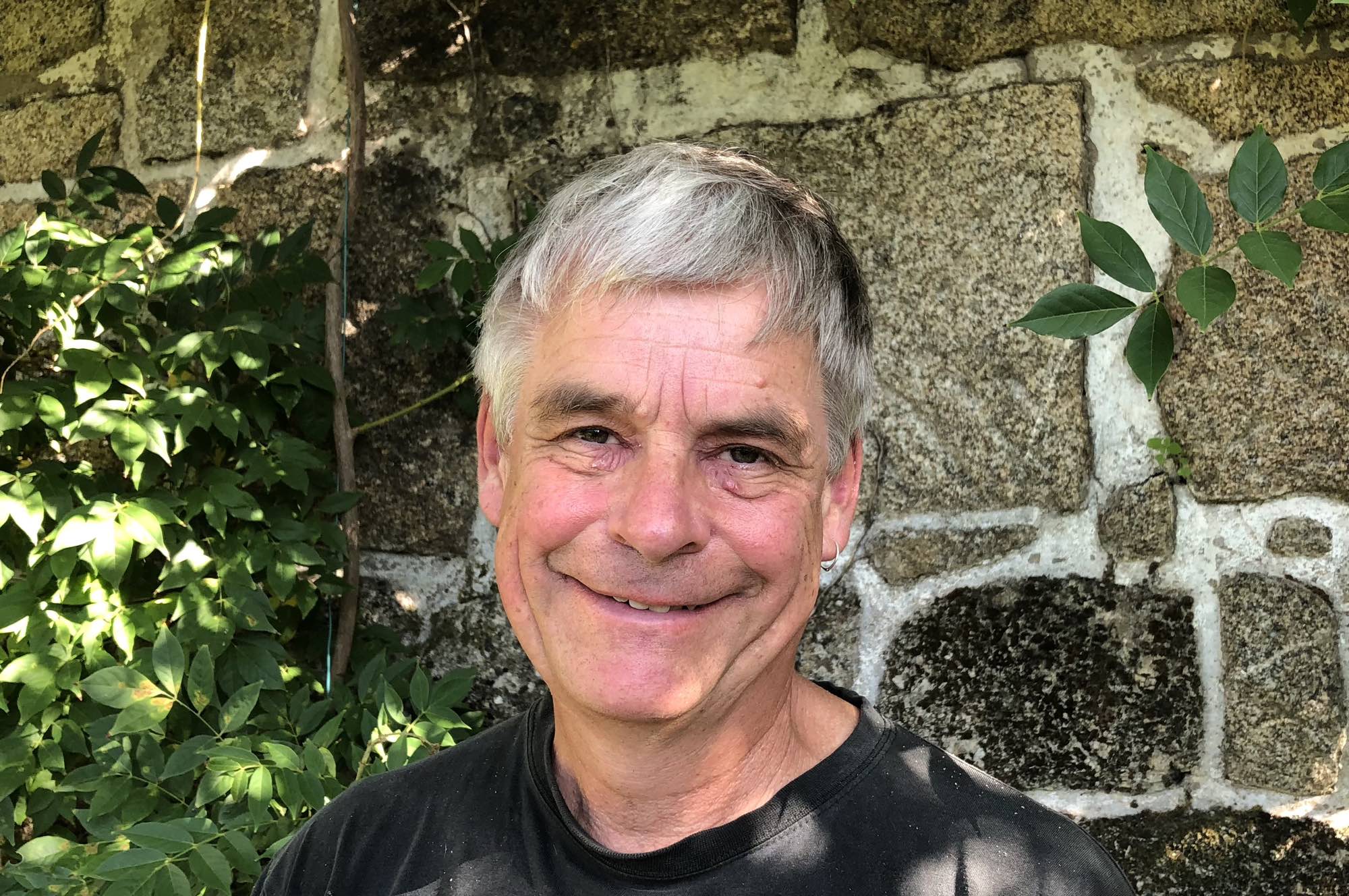 Noel Kingsbury posing in front of a brick wall in a garden