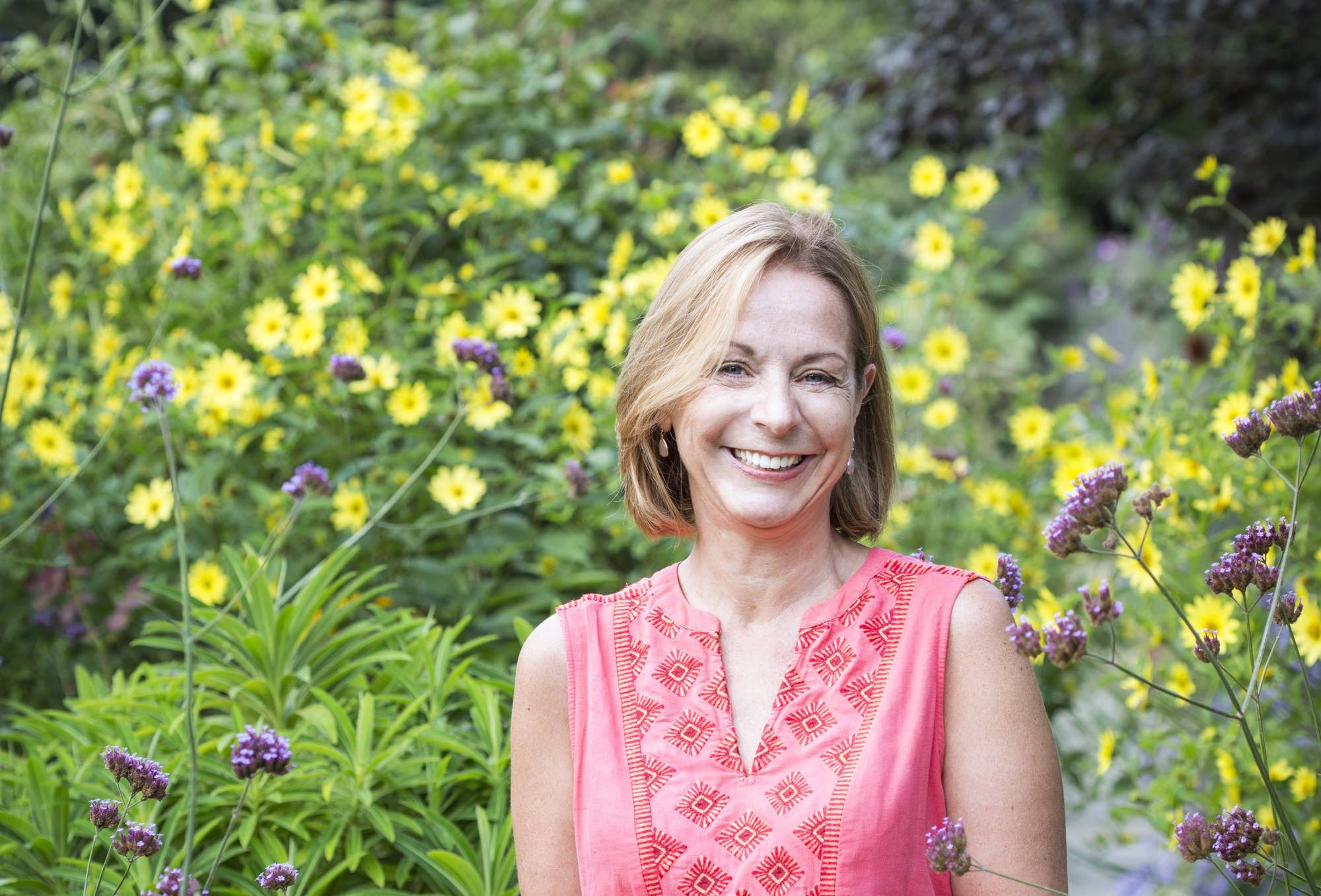 headshot of Jo Thompson taken in front of a background of yellow flowers