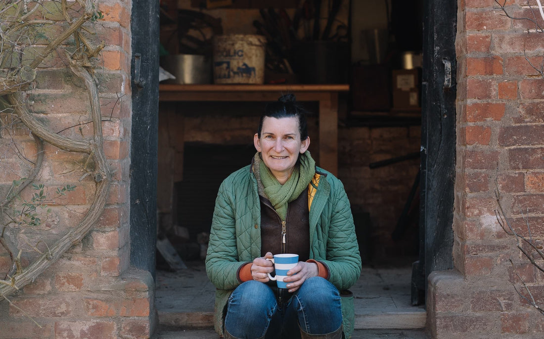 Tamsin Westhorpe sat at the entrance to a home holding a mug of tea