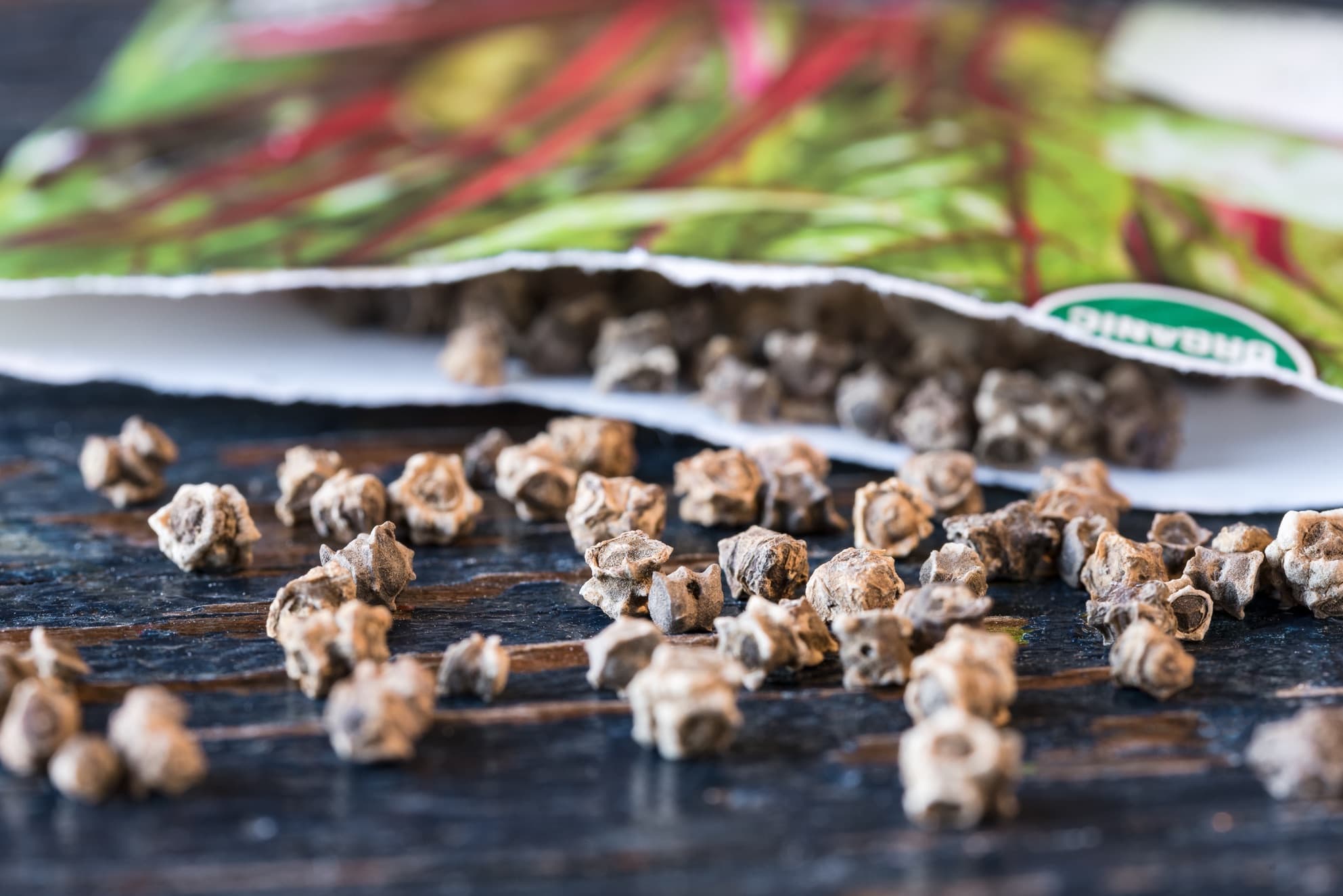 swiss chard seeds spilling out of a packet on to a table