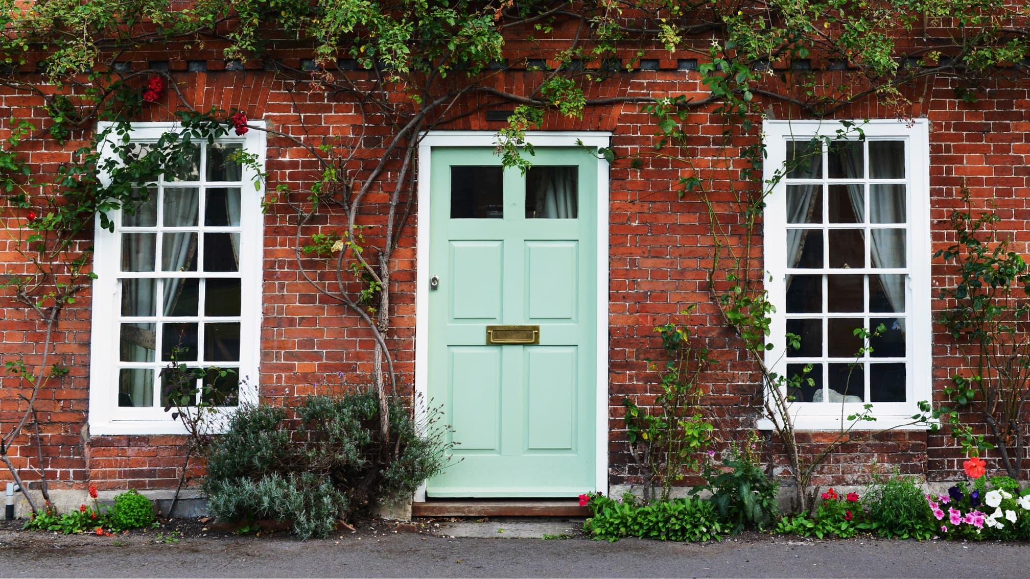 exterior of old country house with turquoise painted front door and climbing plants and shrubs