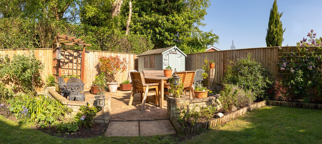 a panoramic view of a garden with patio, furniture and many plants