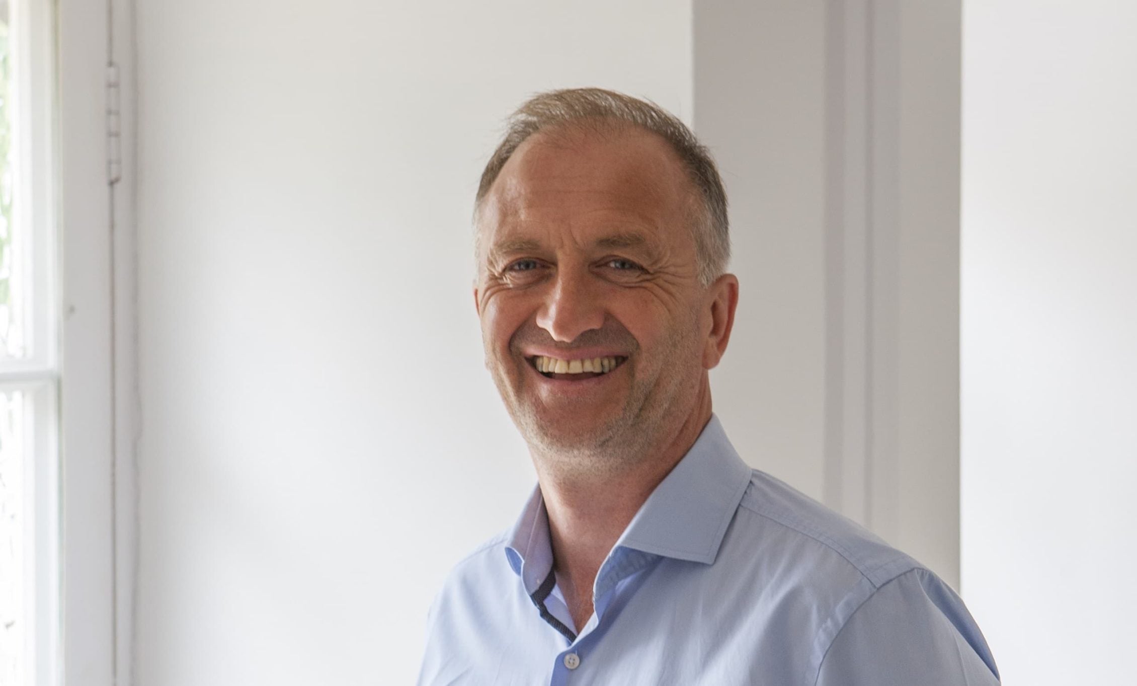Clive Nichols smiling against a white background indoors