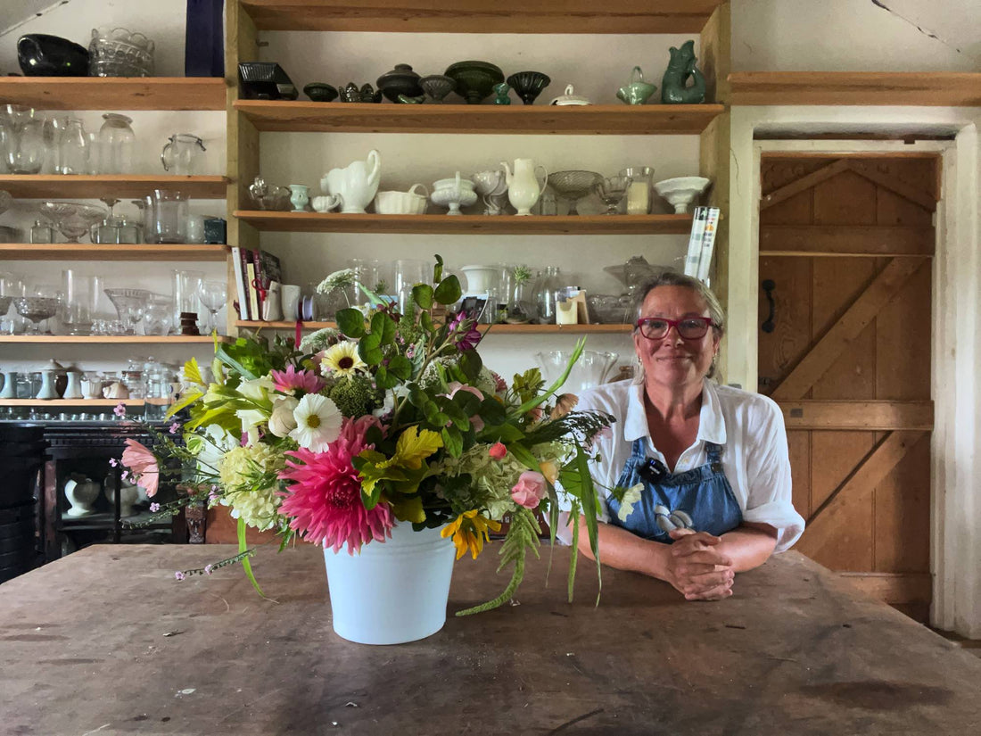 Georgie Newbury posing next to a floral arrangement inside her home