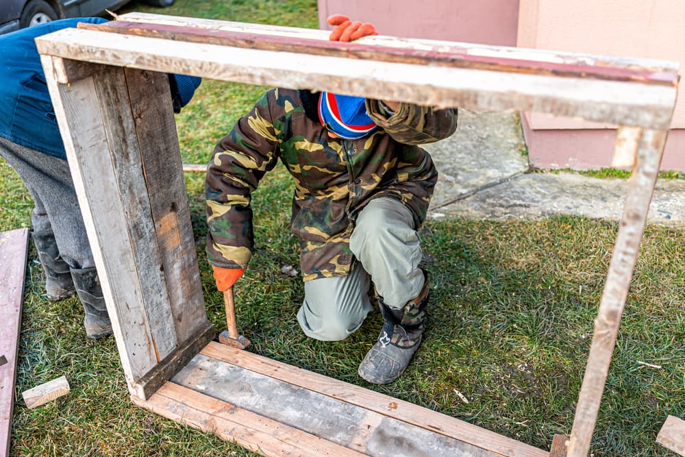 man using hammer to attach cold frame battens to planks