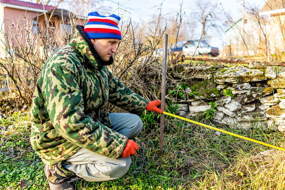 man measuring out an area for placing a cold frame
