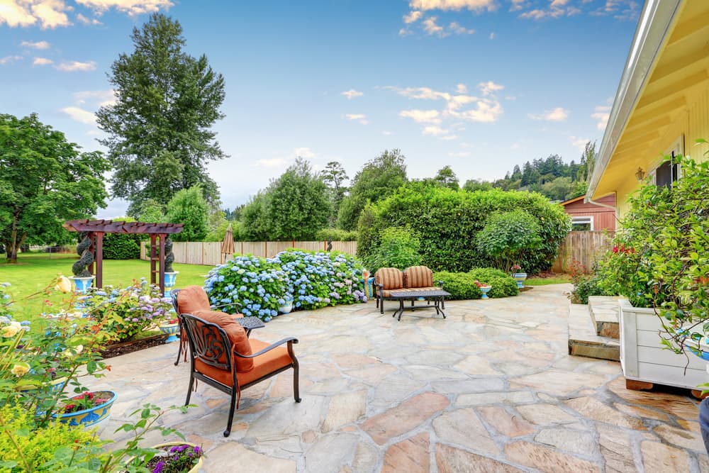 a sprawling garden space with surrounding blue flowering hydrangea and rose bushes