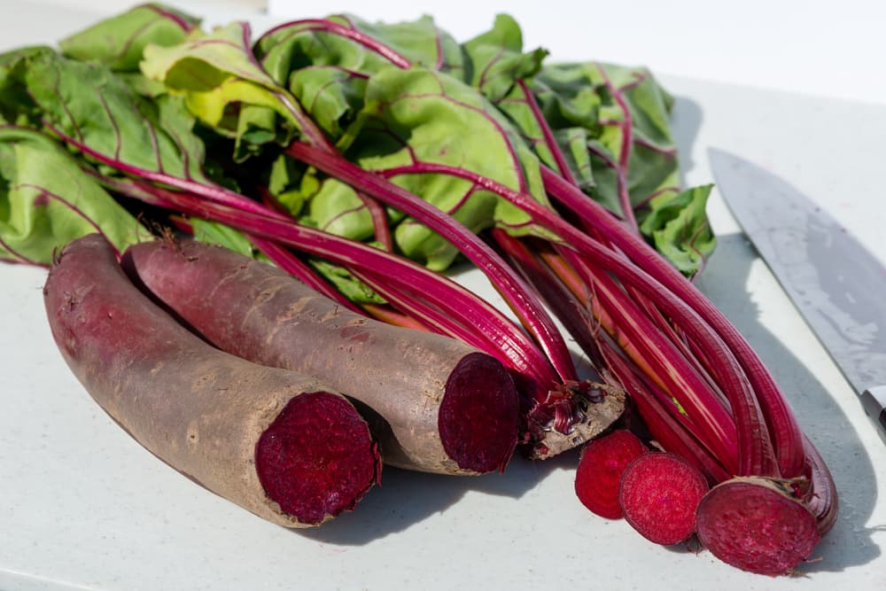 cylindra beets on a chopping board with the leaves sliced off