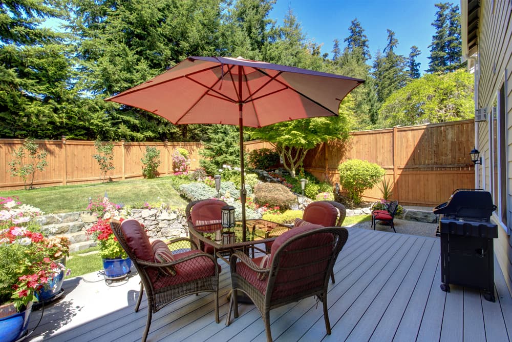 a decked area with a bbq and garden furniture in shade