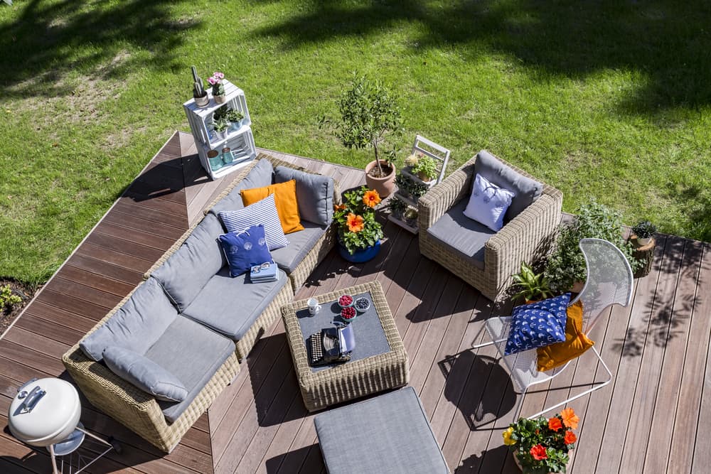 birds eye view of decked garden area with a bbq, potted plants and extensive garden furniture