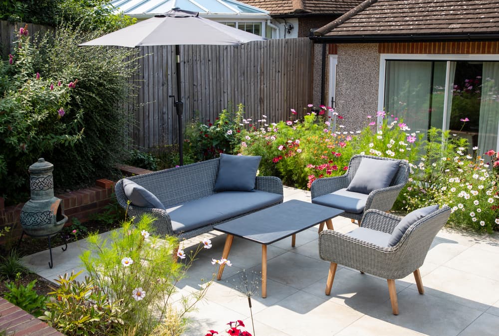 various shrubs and perennials growing either side of patio furniture and a chiminea