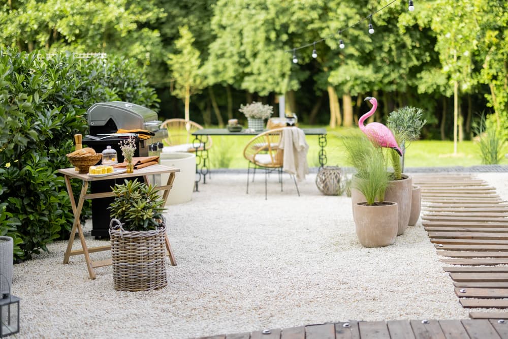a gravel garden with timber steps, ornaments and a bbq