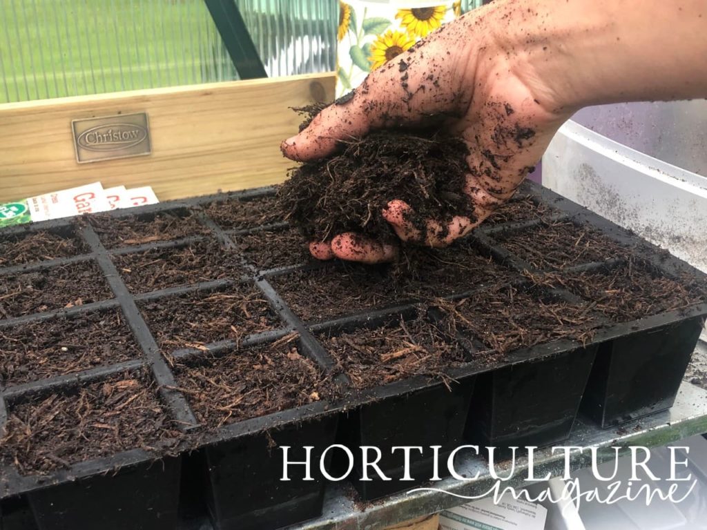 hand filling potting tray with compost