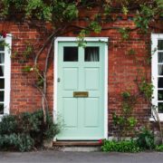 exterior of old country house with turquoise painted front door and climbing plants and shrubs