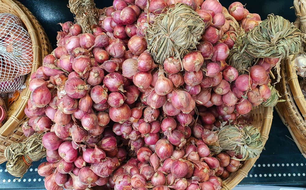 many small red shallots shown in a wicker basket
