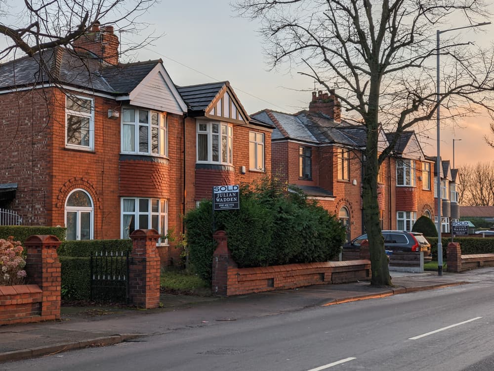 semi detached homes in winter with hedging in the front garden and a 'sold' sign out front