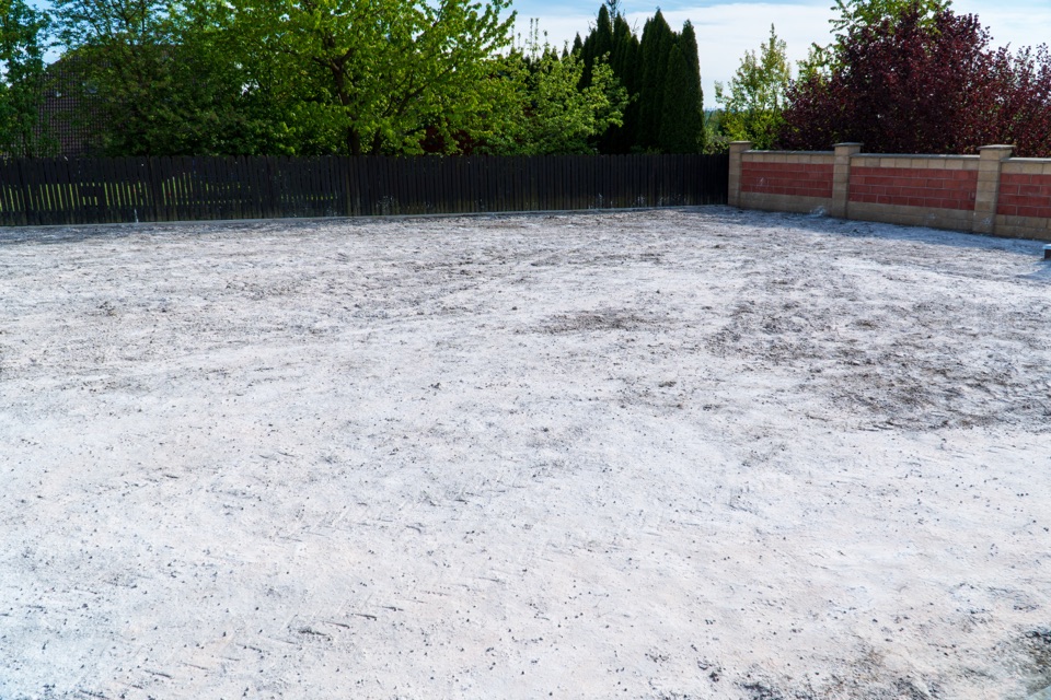 a garden that has completely been surface-level coated in white lime powder with a brick wall and fence on the border