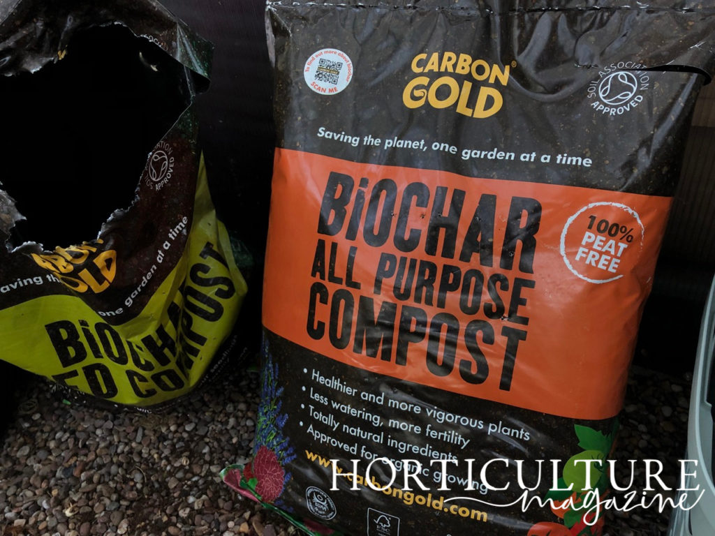 an unopened bag of all-purpose compost with an orange label next to an open bag