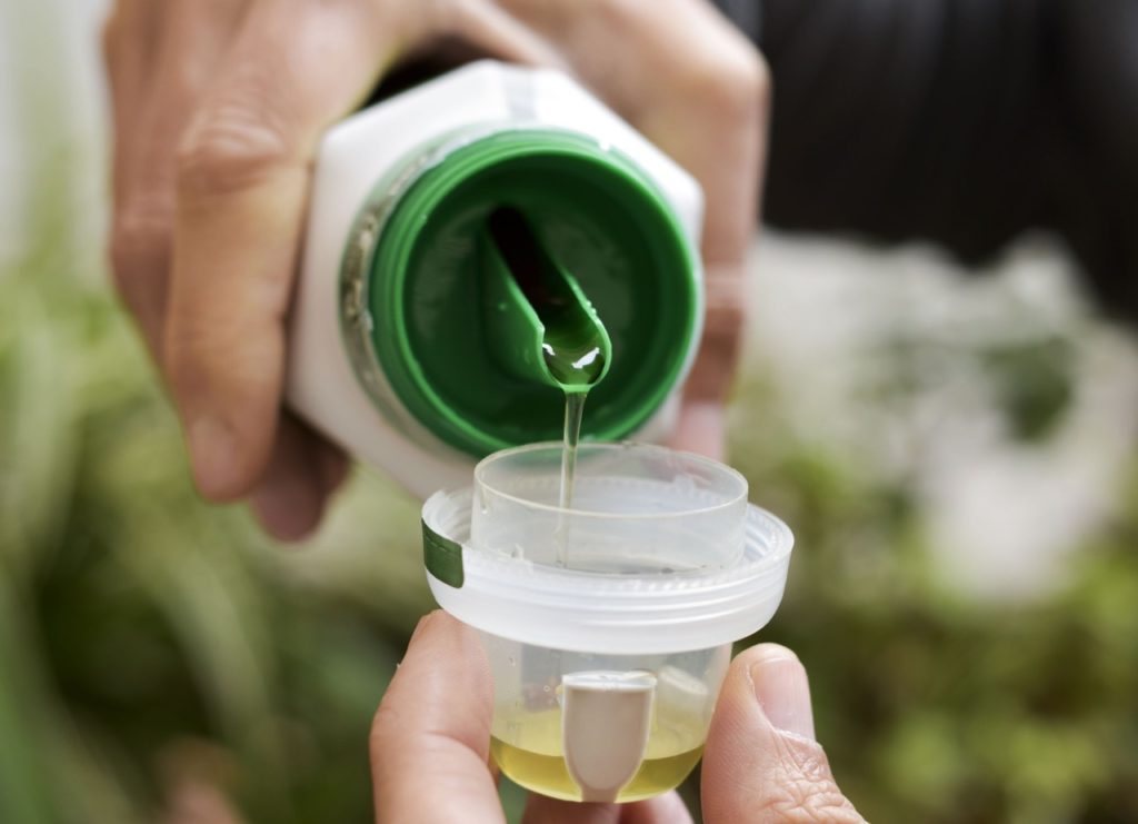 liquid fertiliser being poured out into its lid