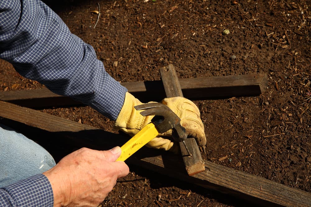 gardener hammering nails into pieces of wood