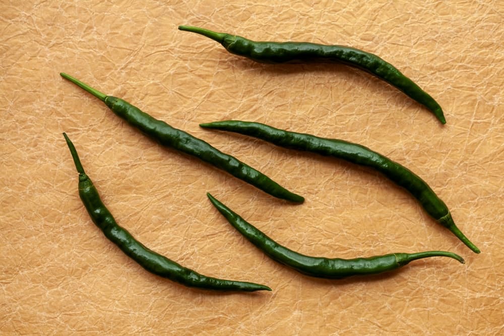 five harvested Pepper Joe's Long Cayenne fruits sat on brown paper surface
