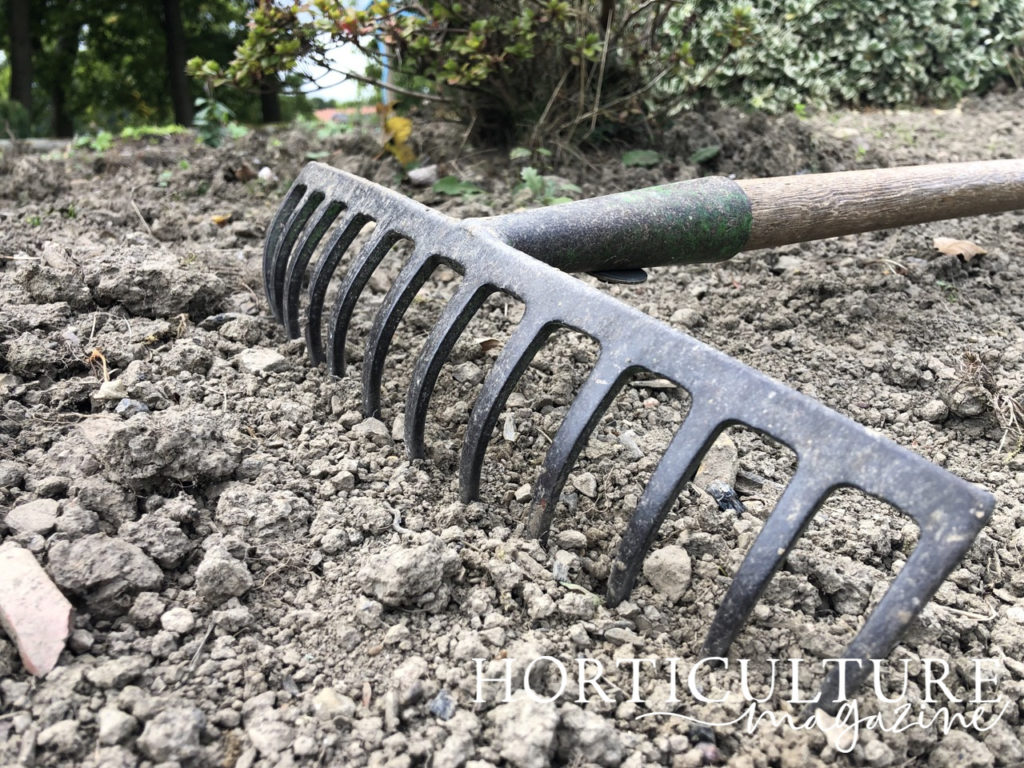a garden rake lying on soil that has just been prepared