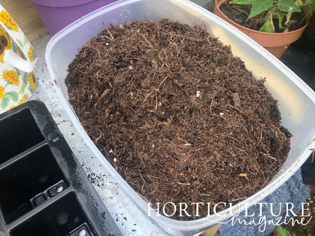 a large container full of compost next to a seed tray