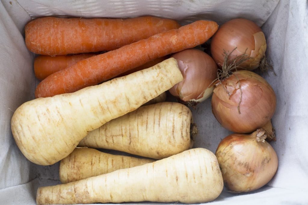 parsnips, carrots and onions stored in a cotton-lined wicker basket