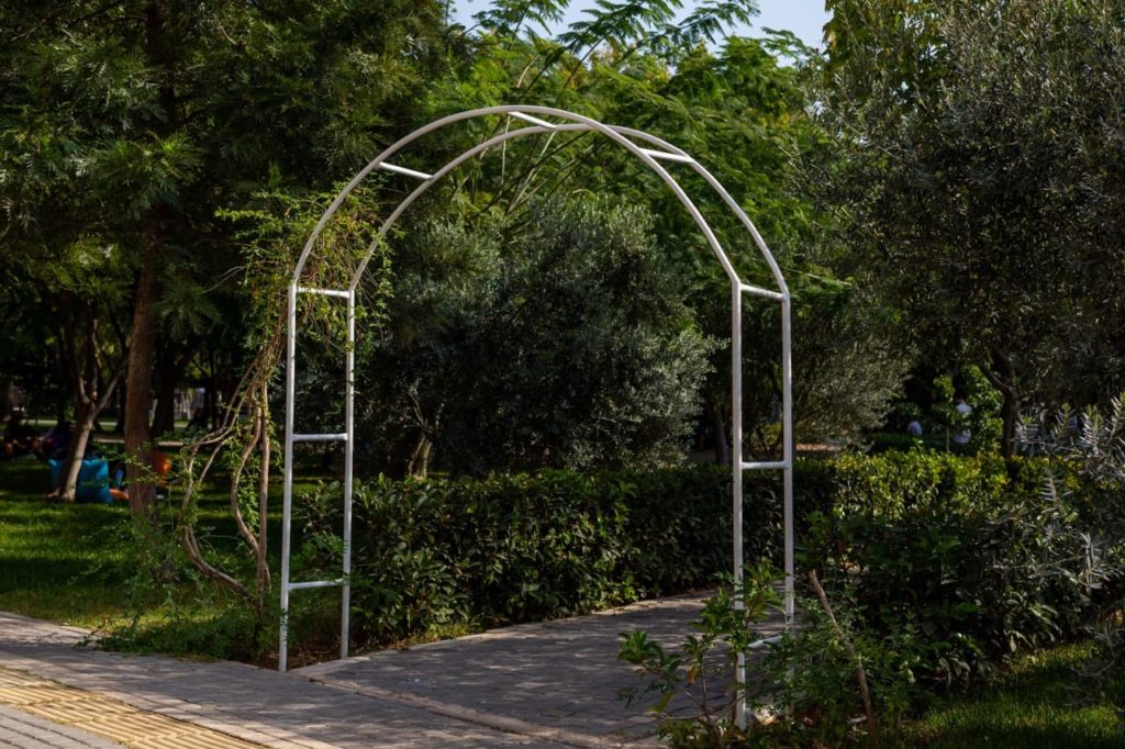 metal trellis with an arched frame placed over a concrete pathway