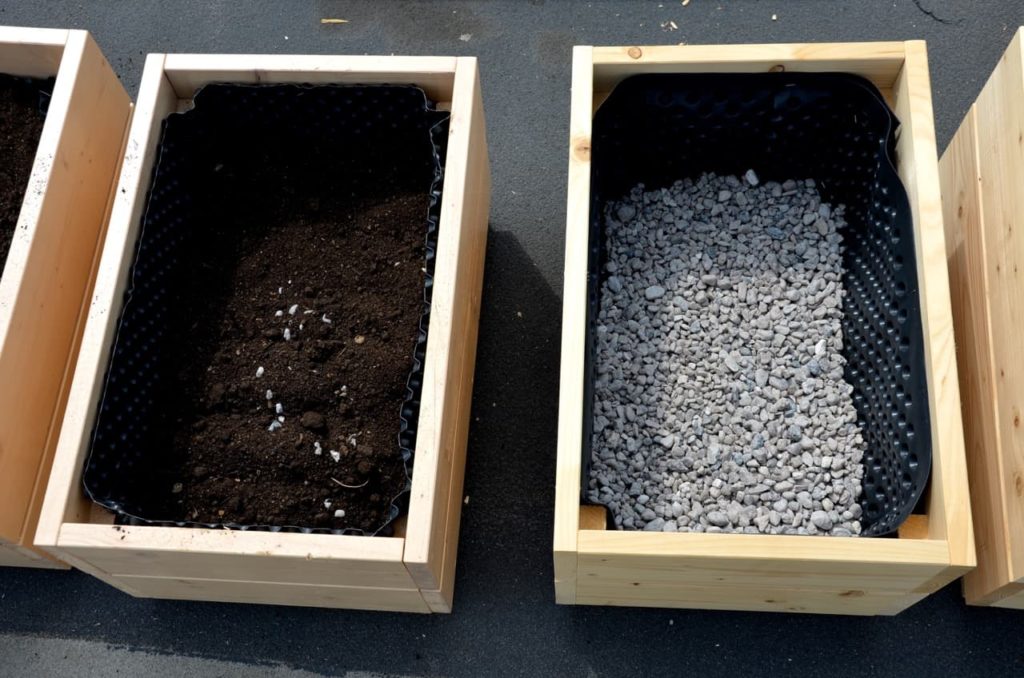large, rectangular wooden planters full of compost and gravel