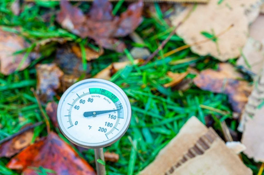 a thermometer being used to measure the temperature of a compost heap