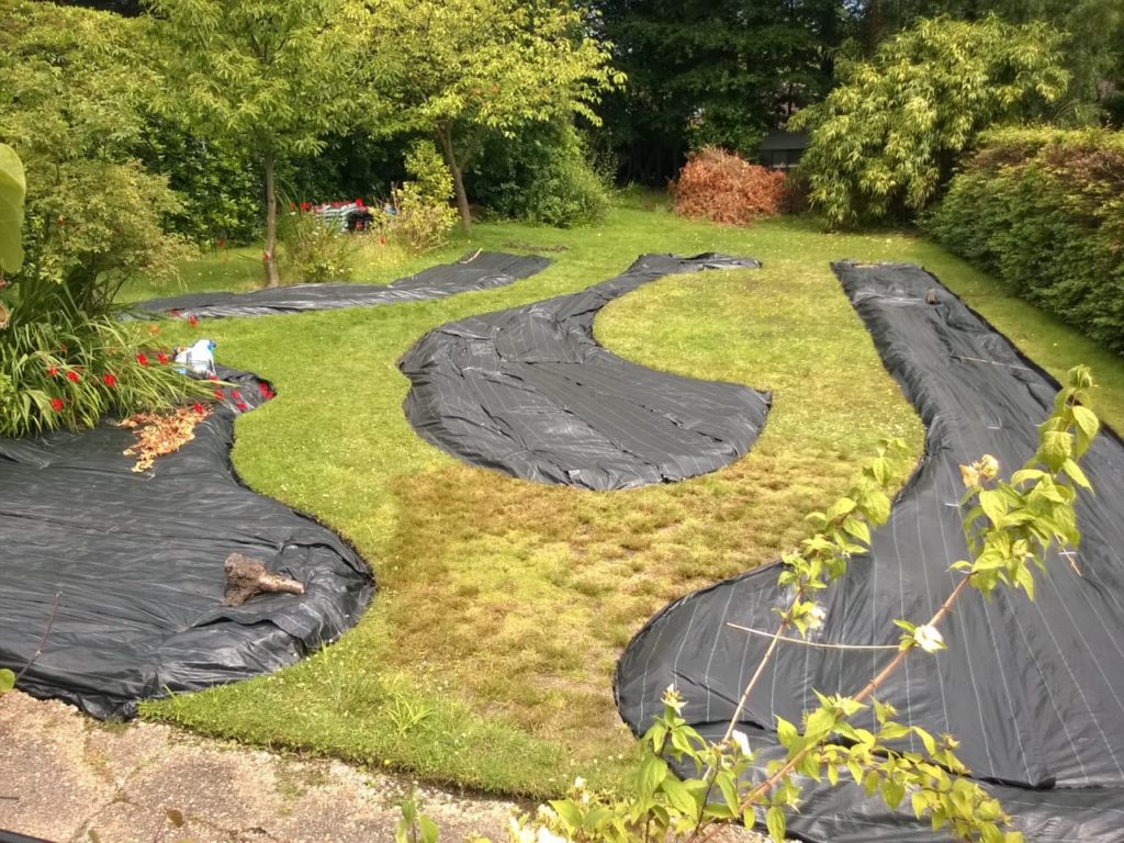 black plastic sheets covering garden beds that have been built into a lawn at 13 Broom Acres