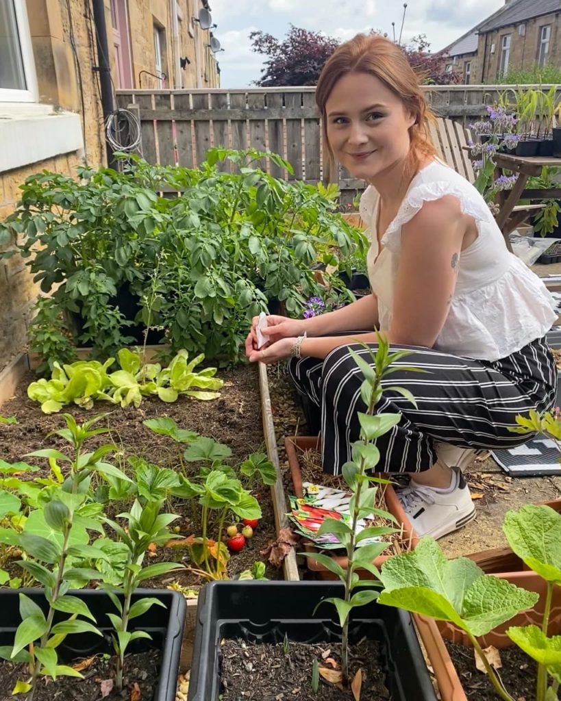 Hannah tending to various plants growing in a garden bed