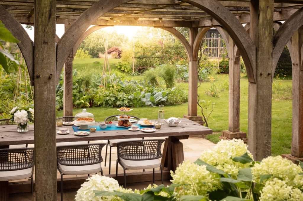 garden designed by Kate Gould with an outdoor table covered with a wooden structure
