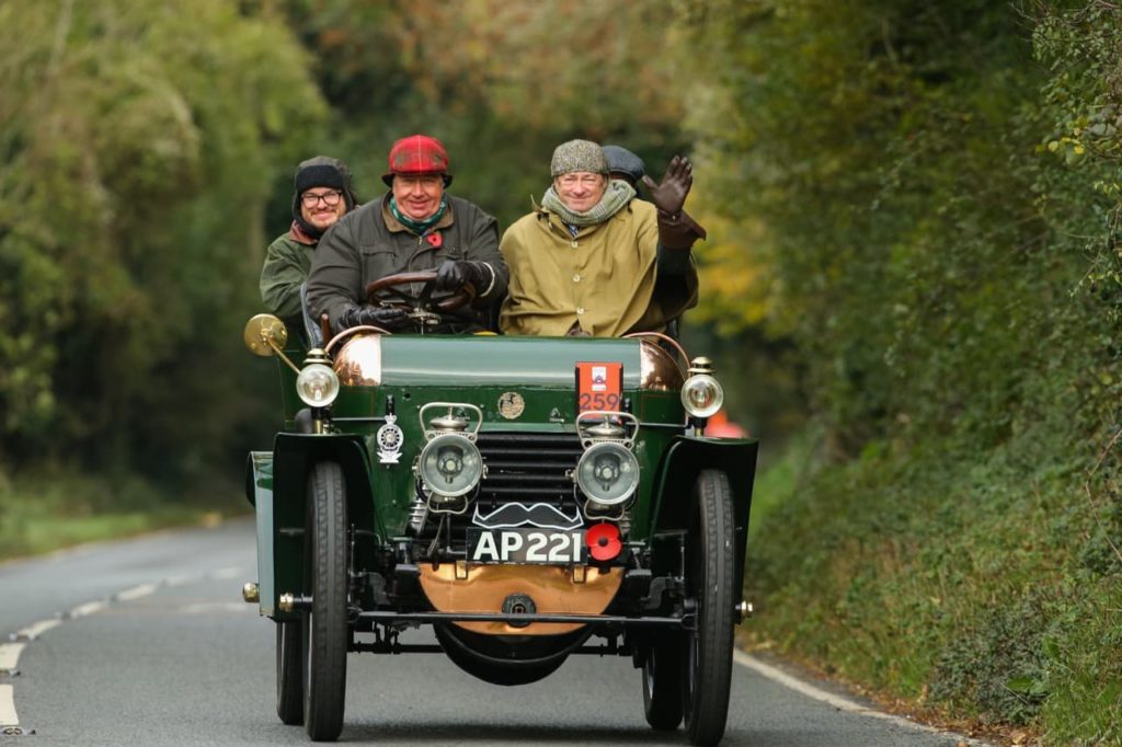 Alan riding in an old-fashioned green car along a country road
