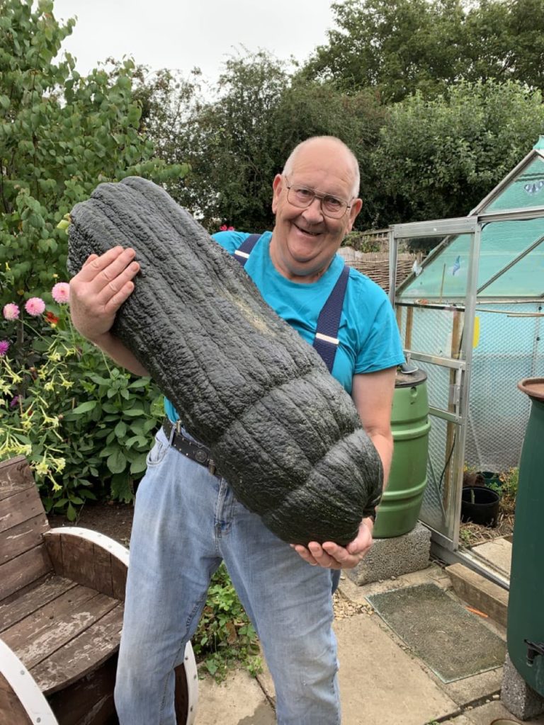 a huge green marrow being held up by a smiling Gerald