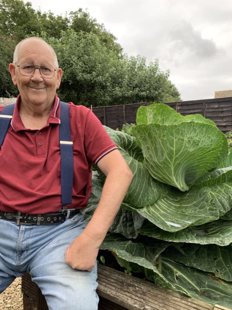 Gerald posing next to a large cabbage plant in his garden