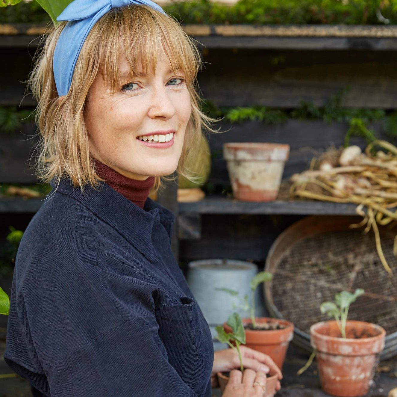 Kathy Slack potting up a vegetable seedling whilst smiling at the camera