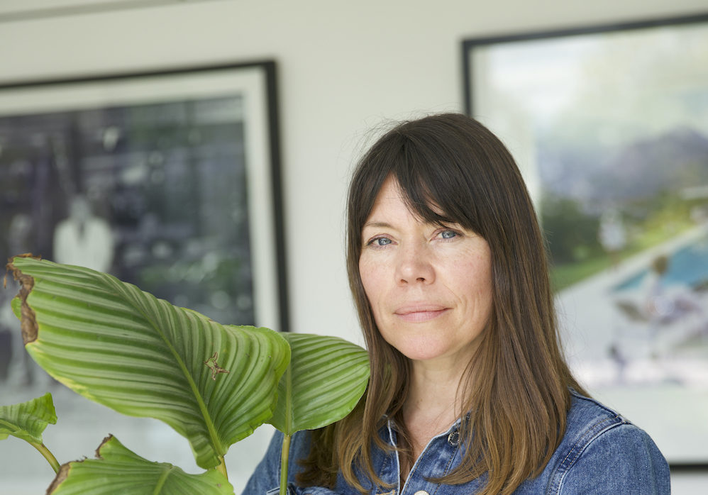Sarah Gerrard-Jones smiling at the camera as she holds up a houseplant