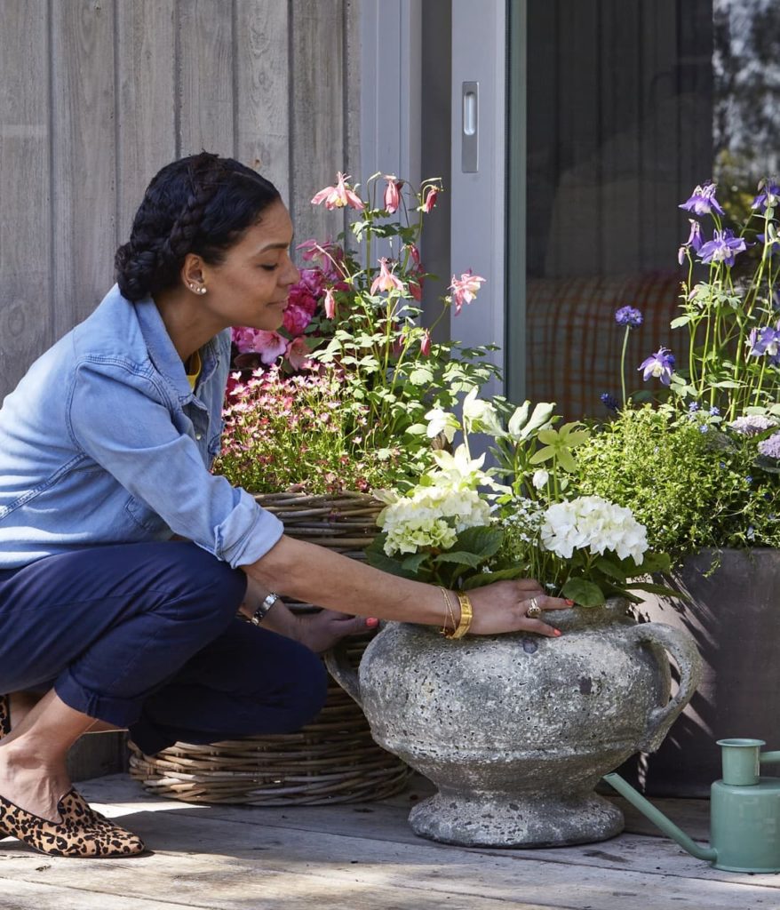 Isabelle Palmer tending to her potted plants, including hydrangea and aquilegia