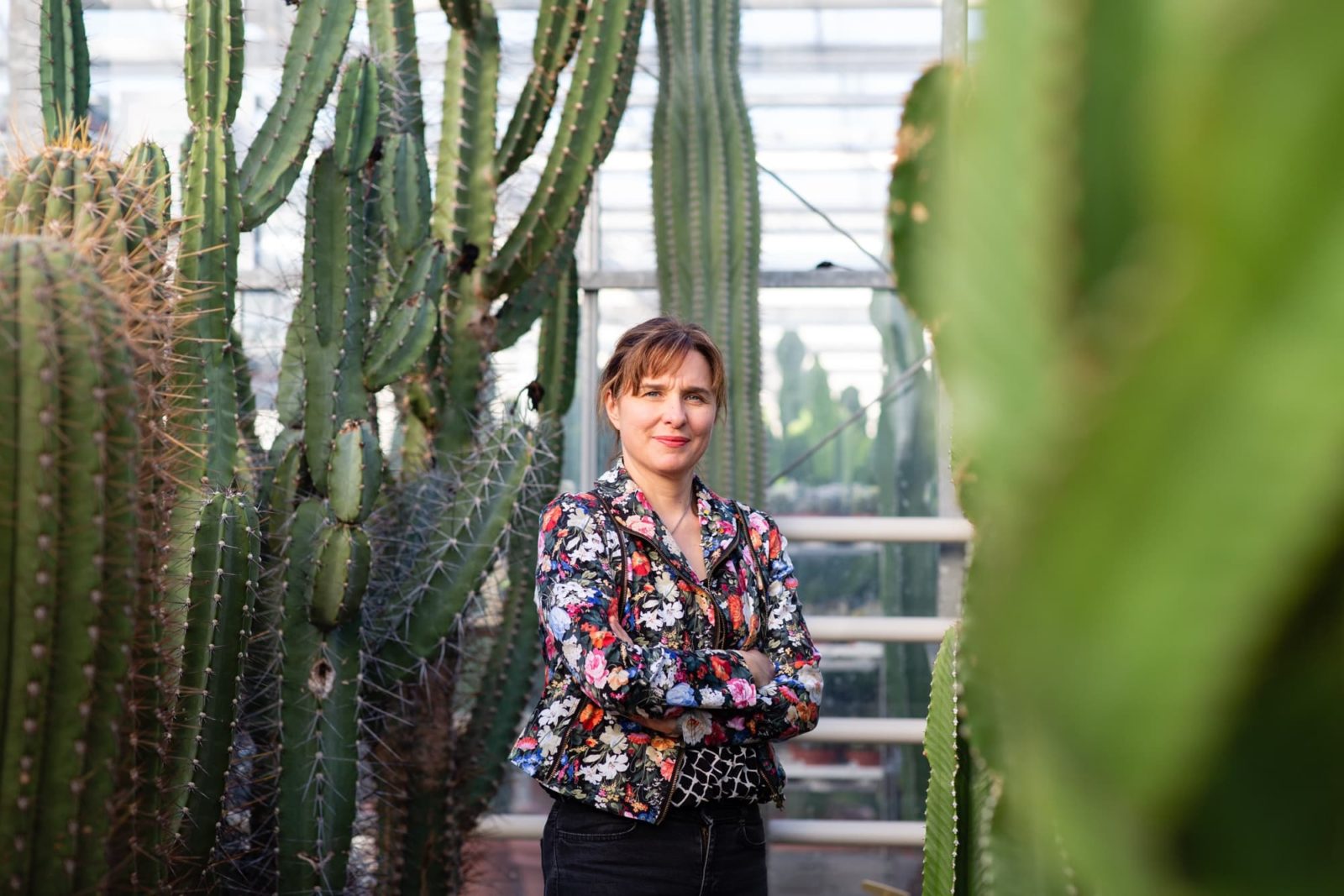 Jane Perrone stood outdoors surrounded by tall cacti plants