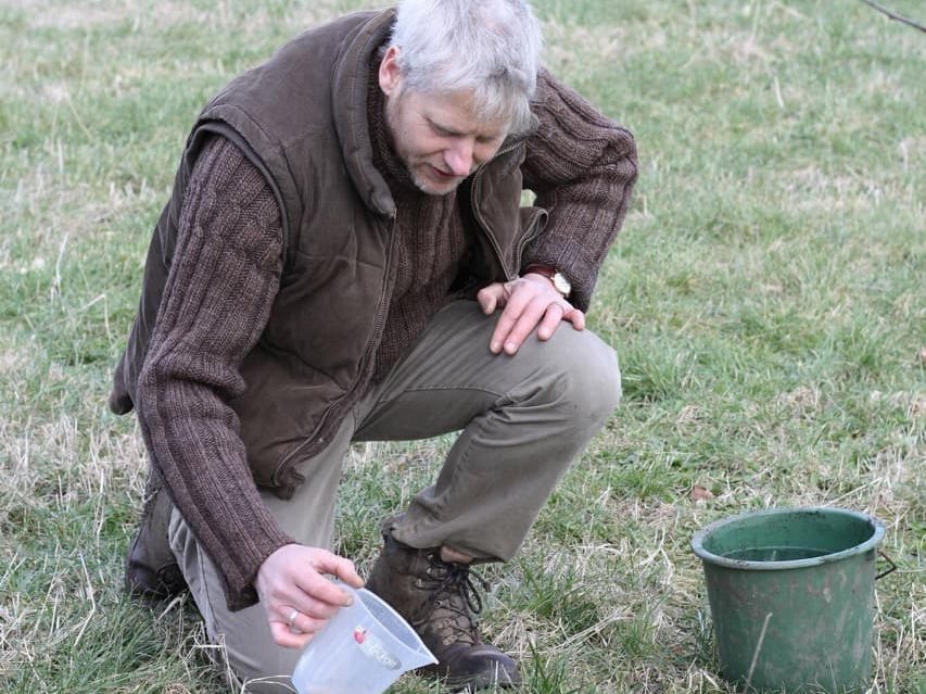 Ben Raskin carrying out a soil infiltration test with a measuring jug