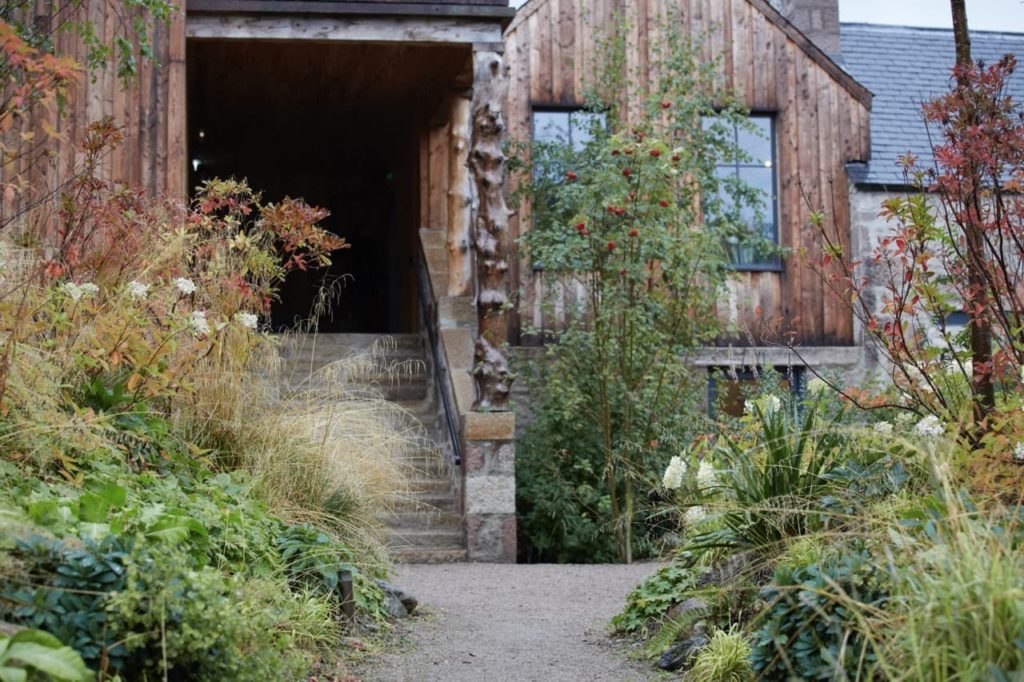 the outside of a timber property featuring many plants