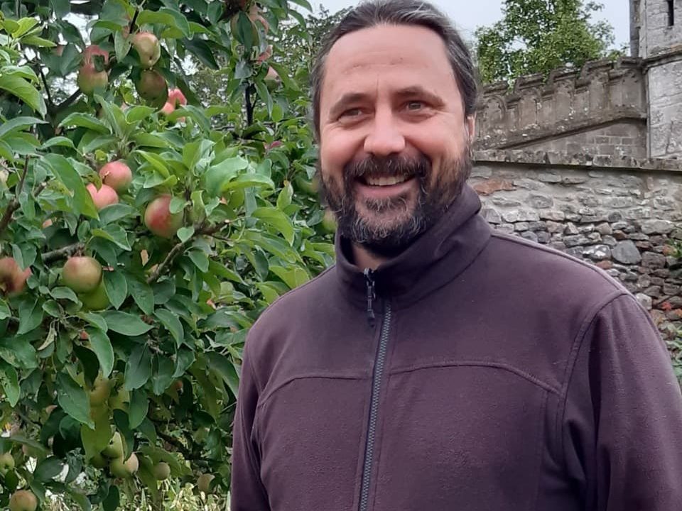 Elliott Beveridge smiling in front of his fruiting apple tree