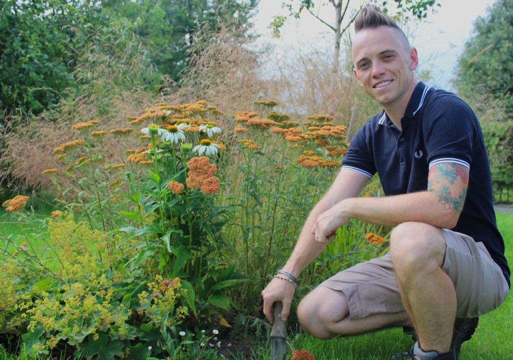 Lee posing in front of flowers and grasses growing in his garden