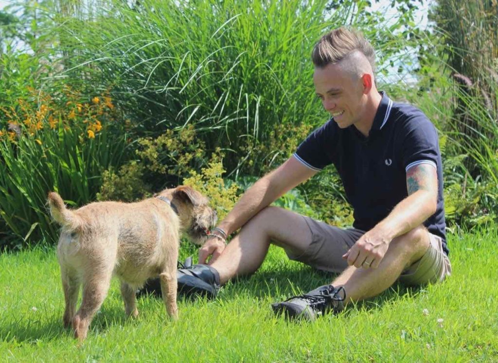 Lee Burkhill sat with his dog on a grass lawn