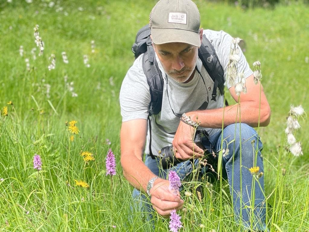 Wes Shaw examining a purple flowering wildflower