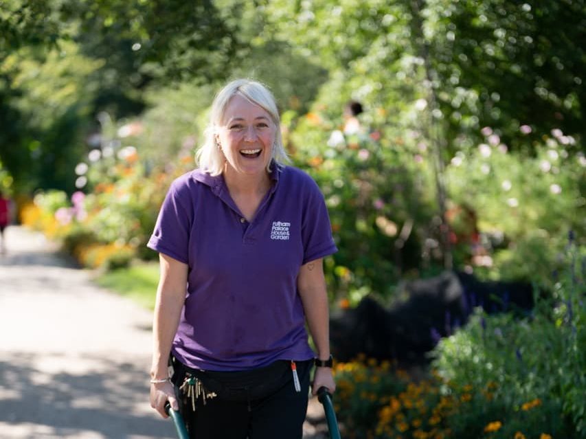 Lucy pushing a wheelbarrow along a path at Fulham Palace Gardens