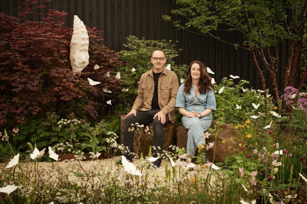 Joe and Laura Carey sat on some large rocks in a garden they designed